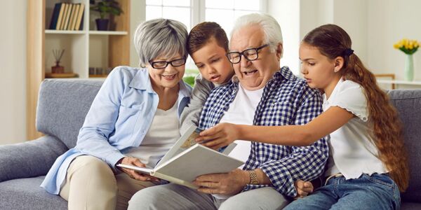 Großeltern mit Kindern lesen in einem Buch über das verantwortliche Wirtschaften der NEUE LÜBECKER